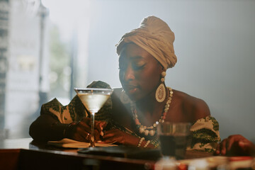 Medium closeup of young Black female jazz musician writing new song while spending evening in local bar
