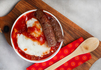Traditional South African Pap, wors and Sheba sauce flat lay with wooden board 
on grey 
