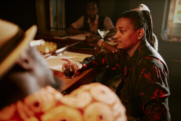 African American musician spending evening in bar after live performance, relaxing, drinking...