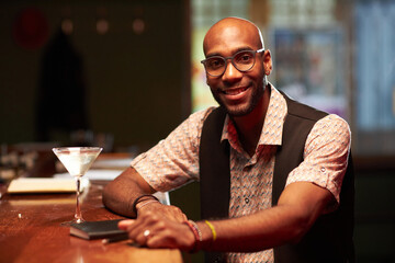 Medium portrait of cheerful young African American man spending evening in local bar smiling at camera