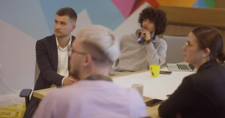 A diverse team of business experts in a modern glass office, attentively listening to a colleague's presentation, fostering collaboration and innovation.