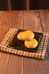 Chinese Pastry Mooncake baked round asian crispy cake with salted yellow red bean paste and eggs yolk in black plate on wood table Traditional halal menu food sweet dessert for autumn festival cafe