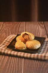 Chinese Pastry Mooncake baked round asian crispy cake with salted yellow red bean paste and eggs yolk in black plate on wood table Traditional halal menu food sweet dessert for autumn festival cafe