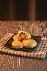 Chinese Pastry Mooncake baked round asian crispy cake with salted yellow red bean paste and eggs yolk in black plate on wood table Traditional halal menu food sweet dessert for autumn festival cafe