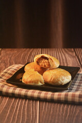 Chinese Pastry Mooncake baked round asian crispy cake with salted yellow red bean paste and eggs yolk in black plate on wood table Traditional halal menu food sweet dessert for autumn festival cafe