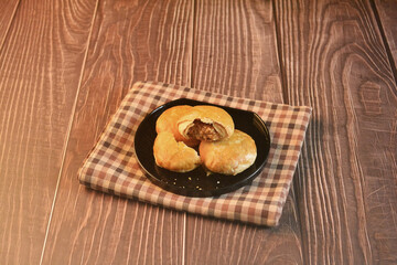 Chinese Pastry Mooncake baked round asian crispy cake with salted yellow red bean paste and eggs yolk in black plate on wood table Traditional halal menu food sweet dessert for autumn festival cafe