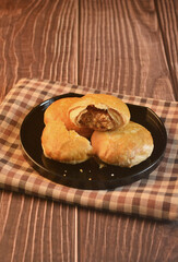 Chinese Pastry Mooncake baked round asian crispy cake with salted yellow red bean paste and eggs yolk in black plate on wood table Traditional halal menu food sweet dessert for autumn festival cafe