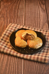 Chinese Pastry Mooncake baked round asian crispy cake with salted yellow red bean paste and eggs yolk in black plate on wood table Traditional halal menu food sweet dessert for autumn festival cafe