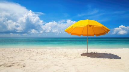 Bright yellow beach umbrella casting shade on a sandy shore, with the ocean in the background