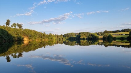 Fototapeta premium A tranquil lake perfectly reflecting the trees in a serene and picturesque landscape