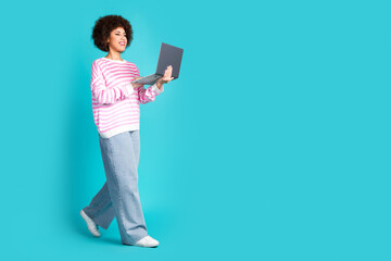 Full size photo of pretty young woman laptop walk empty space wear pullover isolated on teal color...