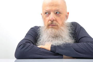 portrait of a serious man with a large gray beard on a light background.