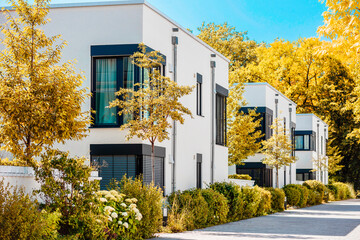 Modern Apartment Building Exterior with White Facade and Trees in Autumn Germany. Contemporary Residential Multifmily Low rise Buildings Townhouse in Autumn Landscaping.