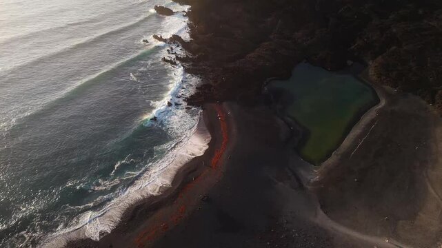Aerial view of the breathtaking Volcan Bermeja and the serene Tiny Charco Verde by the beautiful coastline, El Golfo, Lanzarote, Spain.
