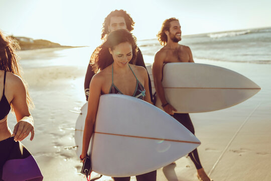 Young male and female surfer walking together on the beach