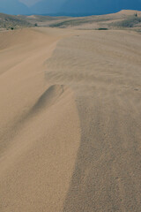 Close-up of wind-swept desert dunes under a cloudy sky