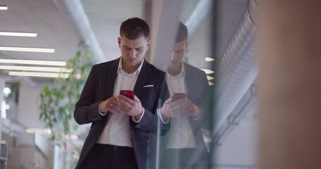 busy businessman in a modern corporate hallway showcases his multitasking skills while using a smartphone