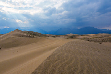 Dramatic desert dunes under sunbeams and cloudy sky