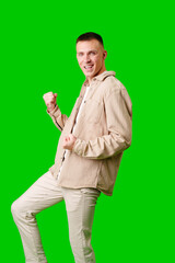 Young Man Celebrates Success With Energetic Pose Against Vibrant Green Background