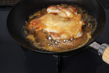 フライパンの上で調理中の日本の鶏モモ肉の照り焼き