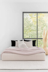 Fototapeta premium Modern minimalist bedroom interior in neutral colors with a bed next to a window and elegant decor.