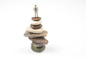 miniature people. the figure of a man stands on top of the stones. concept of achievements in life and success in business.