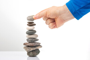 hand builds a pyramid from stacked stones on a white background. stabilization and balance in life