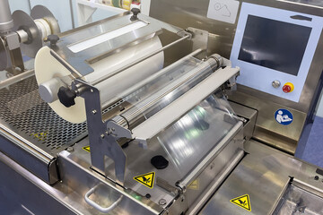 Roll of plastic packaging film on the automatic packing machine in food product factory