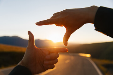 Hands in the shape of picture frame against the sunset