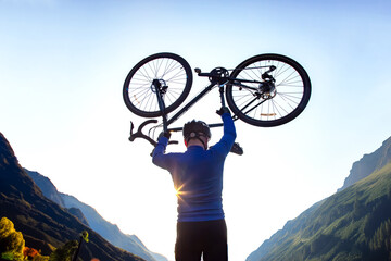 male cyclist with a raised bicycle against the backdrop of the sun and mountains