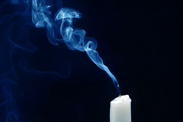 Smoke from an extinguished candle on a dark background. The concept of spirituality and the end of...