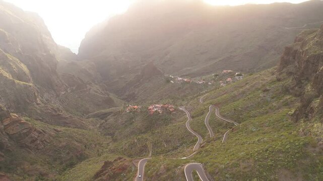 Aerial view of winding road through serene valley with picturesque village and majestic mountains, Masca, Tenerife, Spain.