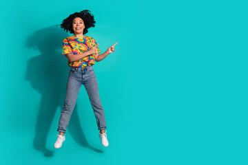 Full length photo of shiny attractive lady dressed retro t-shirt jumping high pointing two fingers empty space isolated blue color background
