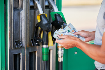 Cropped view of man shocked how much gasoline costs. Driver counting if he has enough money to pay for fuel. Transportation expenses concept.