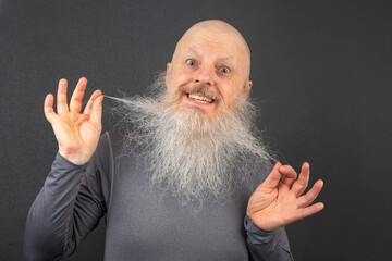 happy bald man extending his arms to demonstrate the fullness and length of his white beard,...
