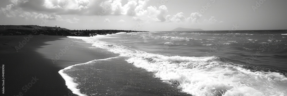 Poster the shoreline displays soft waves rolling in on a black sand beach, with a backdrop of puffy clouds 