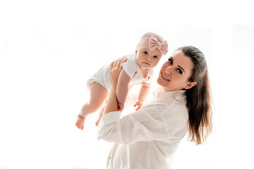 mom and baby hug and kiss at home on the bed in the bedroom, parental love and care, happy...