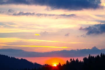 the sky transforms into a dramatic canvas of purples and fiery reds, casting a warm glow across the horizon as the sun dips below, leaving a stunning afterglow