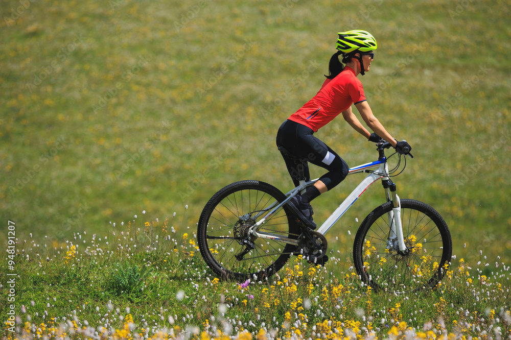 Poster Fitness aisan woman riding mountain bike on beautiful flowering grassland mountain top