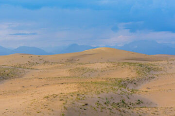 Dramatic desert dunes under sunbeams and cloudy sky