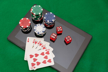 Royal Flush in Hearts with Poker Chips and Dice on Digital Tablet on Green Felt background, Online casino gambling concept