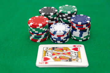 Stacks of poker chips with king of hearts card on green felt casino background