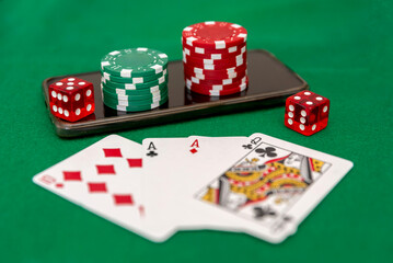 Poker Chips Stacked on a Smartphone with Dice and Playing Cards on Green Felt