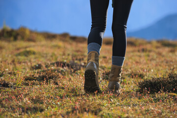 Hiker legs wearing  leather boots hiking on high altitude mountain top