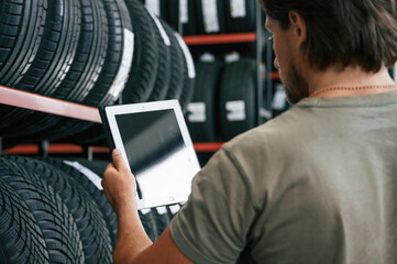 Copy space on the digital tablet. Man is in the tire fitting car service