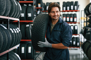 Carrying the tire. Man is in the tire fitting car service