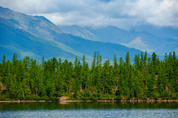 Forest-lined lakeshore with distant mountains