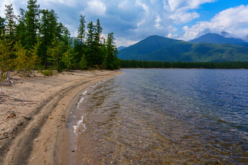 Calm lake with misty mountains and tree-lined shore