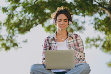 Young excited winner woman wearing shirt casual clothes work hold use laptop pc computer sitting...