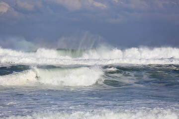 Winter view of big waves with spray by wind at Jeongdongjin Beach against sea horizon and cloud near Gangneung-si, South Korea